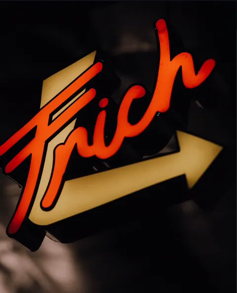 Cartel de neón de Frich con la flecha encendida