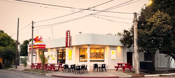 El local de Jesús María al atardecer, con las mesas de picnic rojas en la vereda